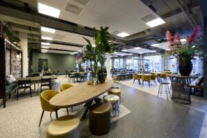 Moderne en sfeervol ingerichte kantine aan de H.J.E. Wenckebachweg met diverse zitplekken en grote kamerplanten.